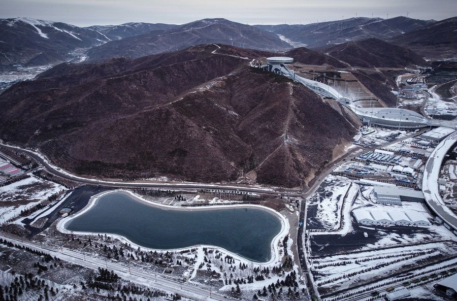 An aerial view shows a reservoir that provides water for snow guns that service competition venues of the Beijing 2022 Winter Olympics in Zhangjiakou, Hebei province, China, 20 November 2021. Pictured in the background is the National Ski Jumping Centre. (Thomas Suen/Reuters)
