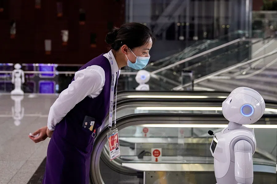A staff member, wearing a face mask following the Covid-19 outbreak, looks at a robot at the venue for the World Artificial Intelligence Conference (WAIC) in Shanghai, China, 9 July 2020. (Aly Song/Reuters)