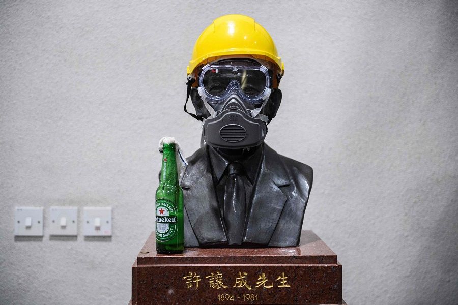 Amidst Hong Kong protests at a university campus on 13 November, a molotov cocktail, gas mask and a yellow construction helmet were placed on a bust of the late hotel tycoon Hui Yeung Shing, known as "King of Hotels". (Anthony Wallace / AFP)