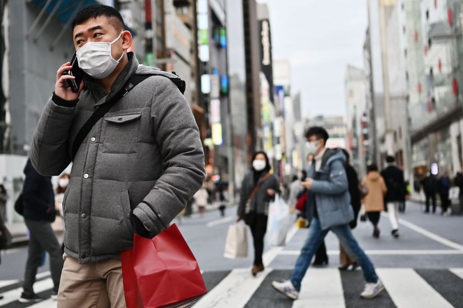 Pedestrians wearing protective masks to help stop the spread of Covid-19, walk on a street in Tokyo's Ginza area on 25 January 2020. (Charly Triballeau/AFP)