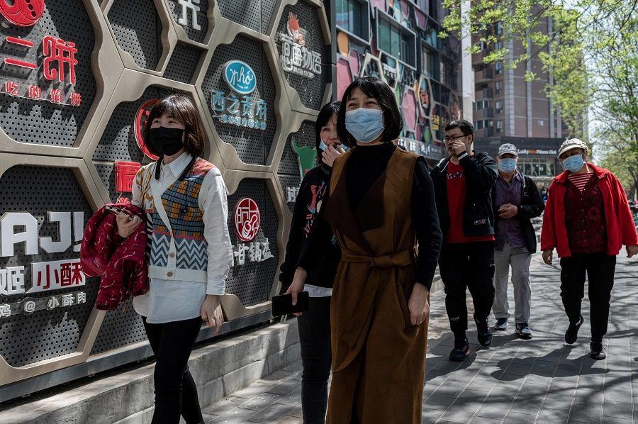 People walk along a street during lunchtime in Beijing, China, on 14 April 2021. (Nicolas Asfouri/AFP)