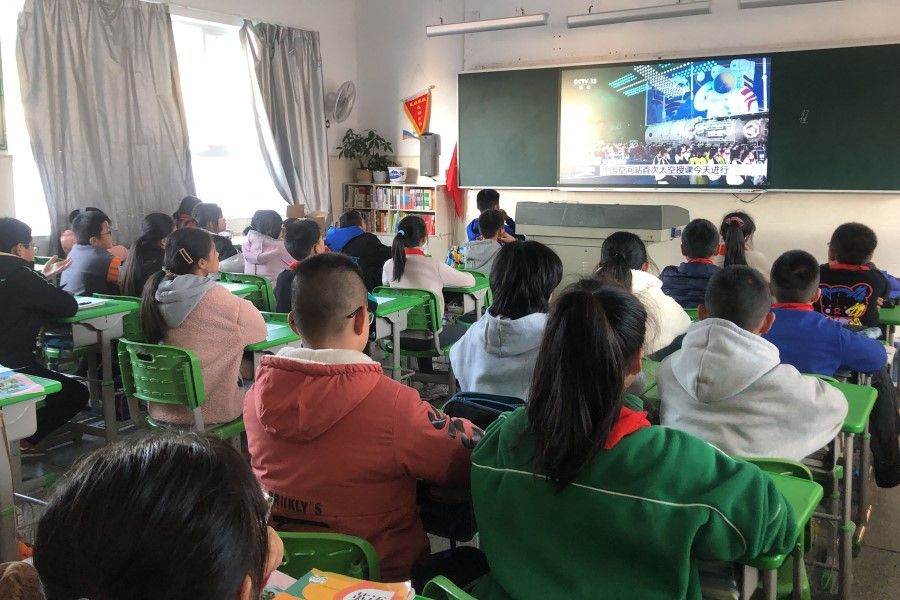 Students watch a live image of a lesson by Chinese astronauts from China's Tiangong space station, at a school in Qingyuan county, Lishui city, in China's eastern Zhejiang province on 9 December 2021. (AFP)