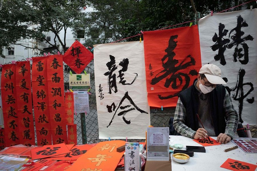 A calligrapher writes blessing ornaments to mark the coming Lunar New Year in Hong Kong's Sheung Wan area on 15 January 2022. (Bertha Wang/AFP)