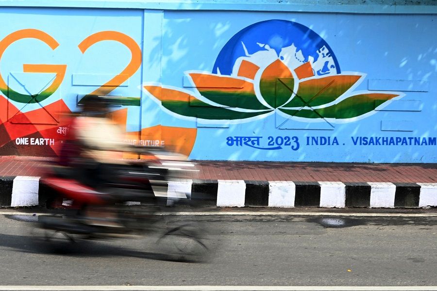 A commuter rides past a wall mural of the G20 Summit logo along a street in Visakhapatnam, India, on 20 March 2023. (Noah Seelam/AFP)