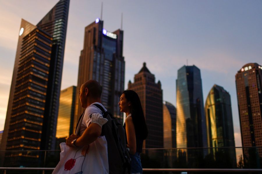 People walk in Lujiazui financial district during sunset in Pudong, Shanghai, China, 13 July 2021. (Aly Song/Reuters)