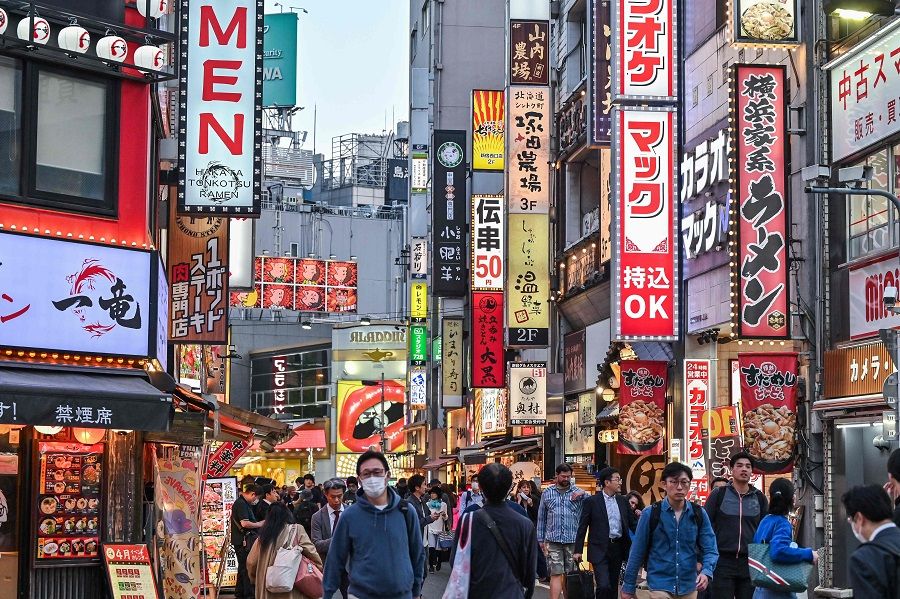 People walk past bars and restaurants along a small street in the Shinjuku area of central Tokyo, Japan on 19 April 2024. (Richard A. Brooks/AFP)