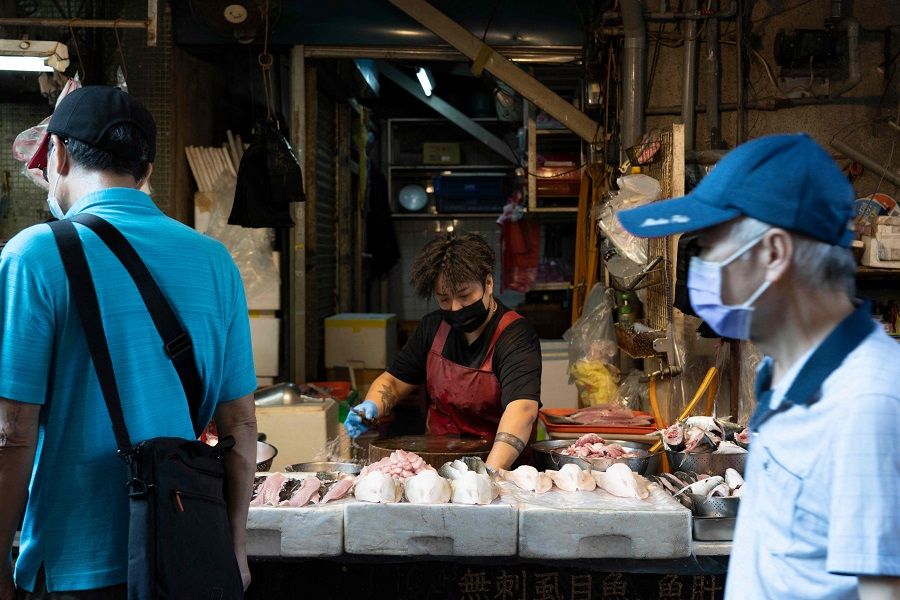 A milkfish vendor waits for customers at a market in Taipei, Taiwan, on 12 August 2022. (Asnaya Chou/AFP)