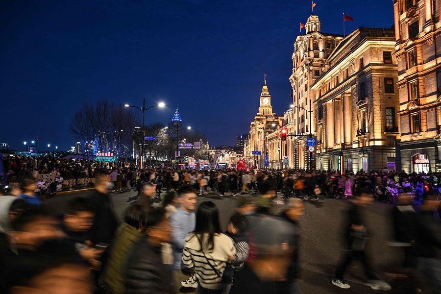 People cross a street on the Bund in Shanghai, China, on 13 February 2024. (Hector Retamal/AFP)