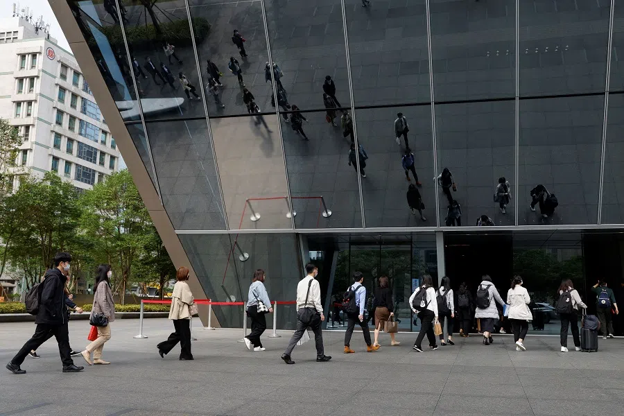 People walk towards the entrance of an office building during morning rush hour in Taipei, Taiwan, 10 April 2023. (Carlos Garcia Rawlins/Reuters)