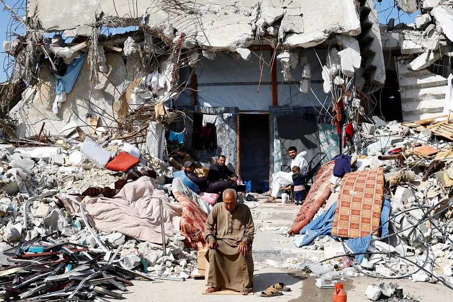 Palestinians sit amidst the rubble of buildings destroyed during the Israeli offensive, amid a ceasefire between Israel and Hamas, in Rafah in the southern Gaza Strip, on 16 February 2025. (Hatem Khaled/Reuters)