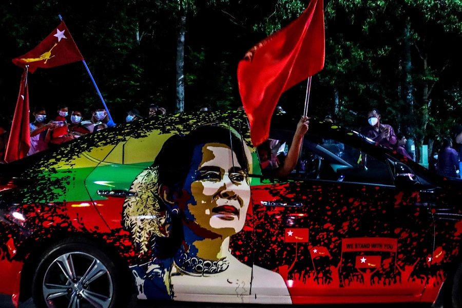 In this file photo taken on 8 November 2020, supporters of the National League for Democracy (NLD) party wave flags, with the car bearing an image of Myanmar's de facto leader Aung San Suu Kyi, in front of the party's office in Mandalay. (Ye Naing Ye/AFP)