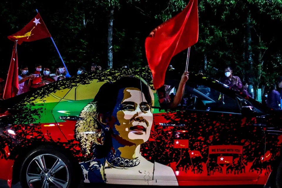 In this file photo taken on 8 November 2020, supporters of the National League for Democracy (NLD) party wave flags, with the car bearing an image of Myanmar's de facto leader Aung San Suu Kyi, in front of the party's office in Mandalay. (Ye Naing Ye/AFP)