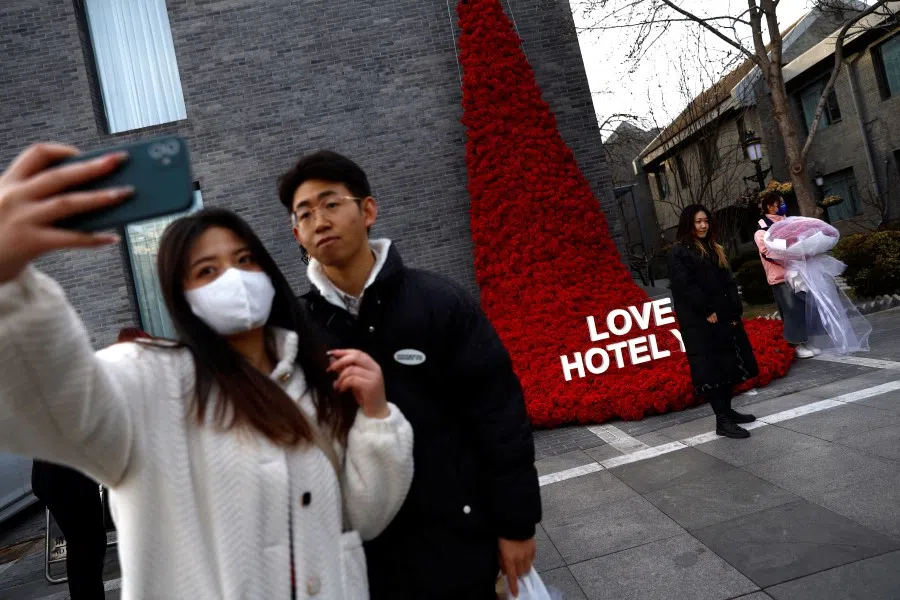 A couple poses for pictures in front of an installation shaped like a rose waterfall, on Valentine's Day in Beijing, China, 14 February 2023. (Tingshu Wang/Reuters)