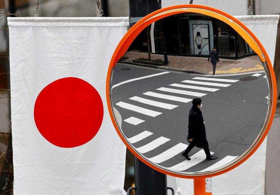 Pedestrians are reflected on a curved mirror next to Japan's national flag in a shopping district in Tokyo, Japan, on 19 March 2024. (Kim Kyung-Hoon/Reuters)