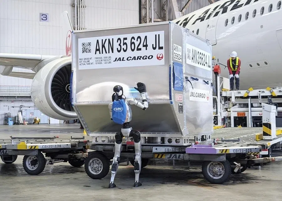 A humanoid robot pushes a cargo container during a media demonstration inside Japan Airlines' airplane hangar at Haneda airport in Tokyo, Japan, on 27 April 2026.