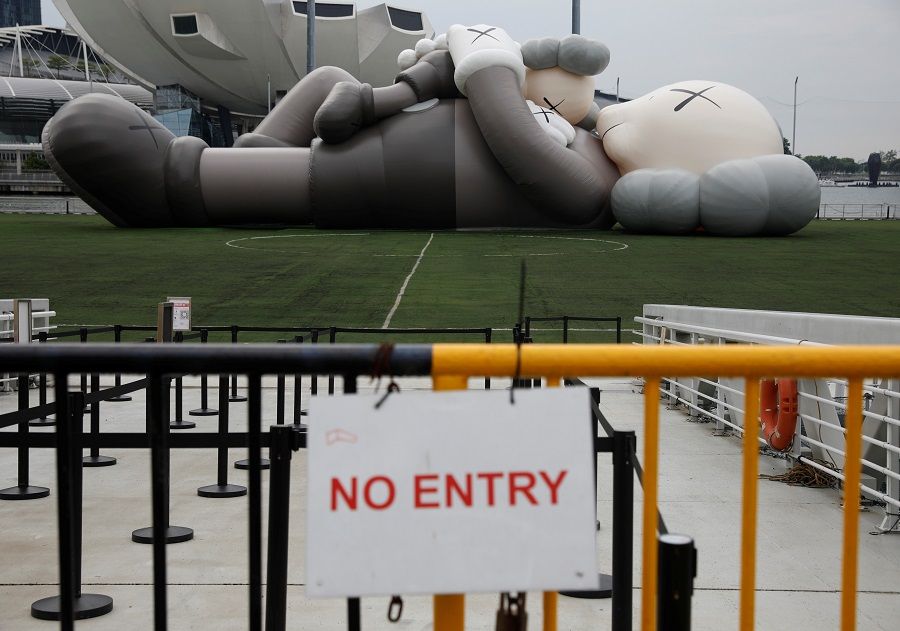 A 42-metre-long KAWS "Companion" inflatable art installation created by artist Brian Donnelly, also known as KAWS, is seen behind closed off barricades as a court ordered the exhibition to be shut down, at Marina Bay in Singapore, 15 November 2021. (Edgar Su/Reuters)