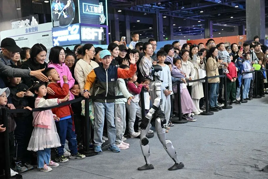 People interact with a humanoid robot from Unitree company during the Beijing Sci-Fi Carnival in Beijing on 28 March 2026. (Adek Berry/AFP)