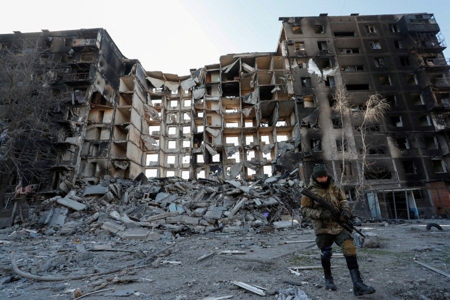 A service member of pro-Russian troops walks near an apartment building destroyed in the course of Russia-Ukraine conflict in the besieged southern port city of Mariupol, Ukraine, 28 March 2022. (Alexander Ermochenko/Reuters)