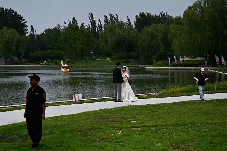 A wedding couple pose for pictures at Chaoyang Park in Beijing, on 21 July 2024. (Pedro Pardo/AFP)
