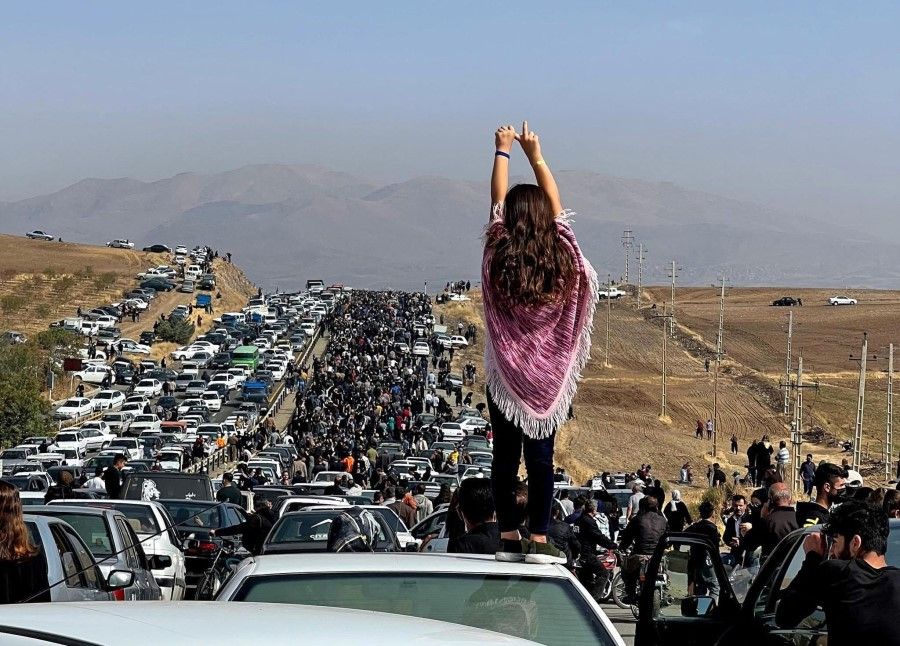 This UGC image posted on Twitter reportedly on 26 October 2022 shows an unveiled woman standing on top of a vehicle as thousands make their way towards Aichi cemetery in Saqez, Mahsa Amini's home town in the western Iranian province of Kurdistan, to mark 40 days since her death, defying heightened security measures as part of a bloody crackdown on women-led protests. (UGC/AFP)