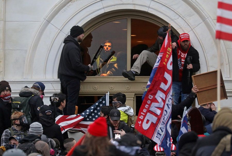 A mob of supporters of then-US President Donald Trump climb through a window they broke as they storm the US Capitol Building in Washington, US, 6 January 2021. (Leah Millis/File Photo/Reuters)