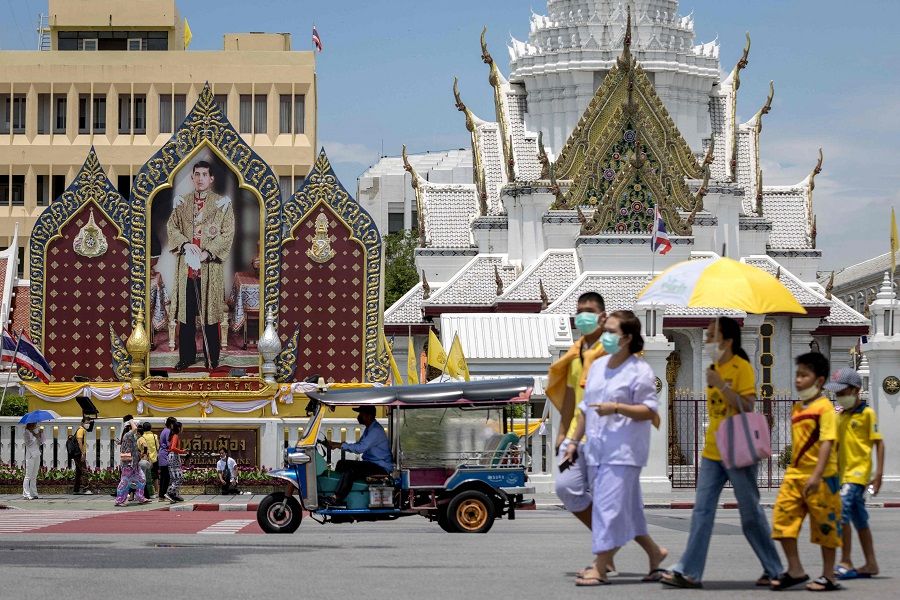 People walk past a portrait of Thailand's King Maha Vajiralongkorn in front of the Grand Palace on the occasion of his 70th birthday in Bangkok, Thailand, on 28 July 2022. (Jack Taylor/AFP)
