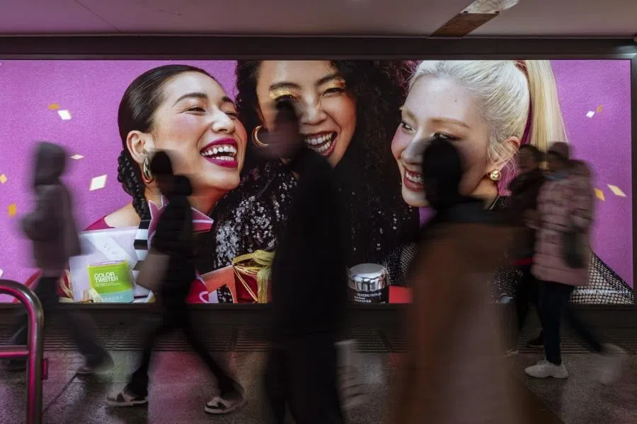 Pedestrians pass an advertisement in the Nanjing East Road shopping area in Shanghai, China, on 19 February 2026.