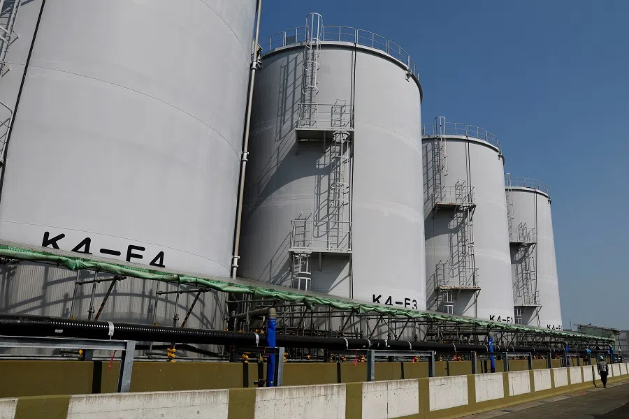 A worker walks past tanks with Advanced Liquid Processing System (ALPS) treated water, at the disabled Fukushima Daiichi nuclear power plant in Okuma town, Fukushima prefecture, Japan, 8 March 2023. (Kim Kyung-Hoon/Reuters)