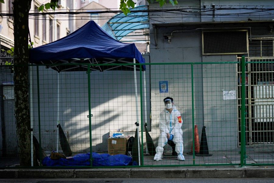 A worker in a protective suit sits at a sealed area, after the lockdown placed to curb the Covid-19 outbreak was lifted in Shanghai, China, 8 June 2022. (Aly Song/Reuters)