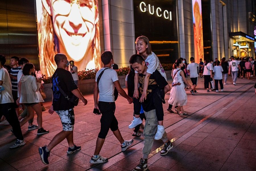 People walk on a street surrounded by shops and malls in Shanghai on 31 July 2020. (Hector Retamal/AFP)