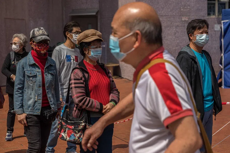 People wait in a queue to receive a shot of the BioNTech Covid-19 vaccine outside a mobile station set up in a residential estate in Hong Kong on 4 March 2022. (Dale de la Rey/AFP)