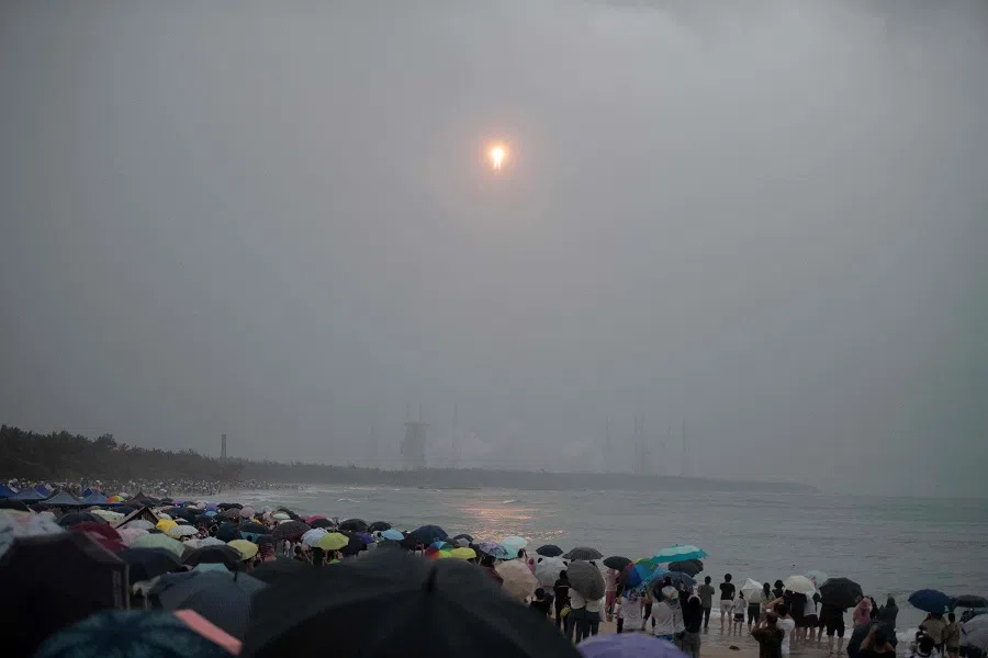 A crowd watches from a beach as a Long March 5 rocket, carrying the Chang’e-6 mission lunar probe, lifts off as it rains at the Wenchang Space Launch Centre in southern China’s Hainan Province on 3 May 2024.