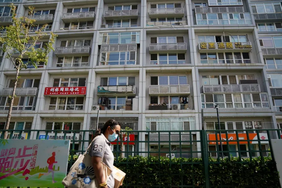 A woman wearing a face mask following the coronavirus disease (COVID-19) outbreak walks past a residential compound in Beijing, China, 11 August 2020. (Tingshu Wang/REUTERS)