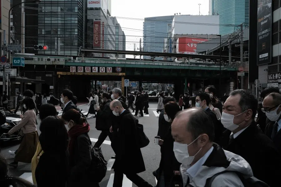 Pedestrians wearing protective masks cross a road in the Shimbashi district of Tokyo, Japan, on 22 March 2021.(Soichiro Koriyama/Bloomberg)
