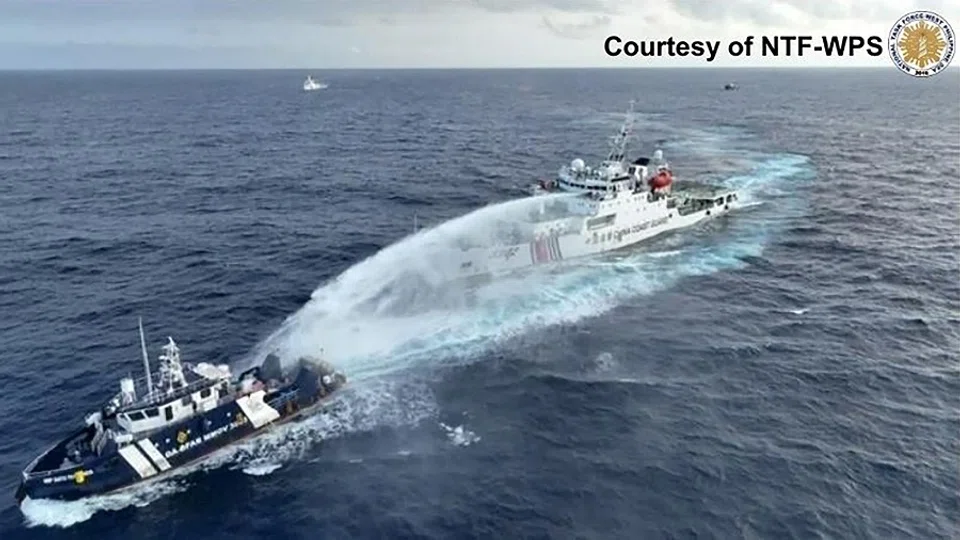 This handout taken and released on 4 December 2024 by the National Task Force for the West Philippine Sea (NTF-WPS) shows a China Coast Guard ship (right) deploying water cannon at the Phillipine Bureau of Fisheries and Aquatic Resources (BFAR) vessel BRP Datu Pagbuaya (left) near Scarborough Shoal in disputed waters of the South China Sea. (Handout/National Task Force for the West Philippine Sea (NTF-WPS)/AFP)