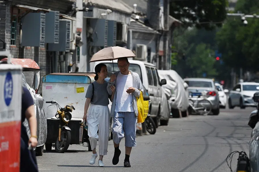 A couple shelter from the sun under an umbrella in Beijing, China, on 23 June 2023. (Greg Baker/AFP)