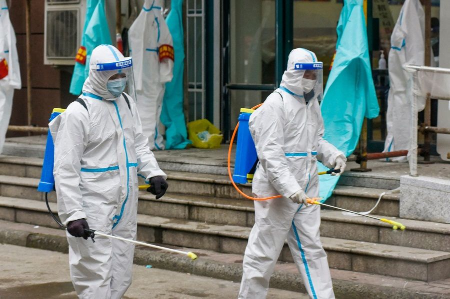 This photo taken on 14 December 2021 shows staff members spraying disinfectant at a residential area in Ningbo, Zhejiang province, China. (AFP)