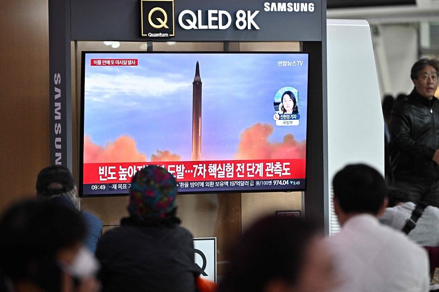 People sit near a television showing a news broadcast with file footage of a North Korean missile test, at a railway station in Seoul, South Korea, on 6 October 2022. (Anthony Wallace/AFP)