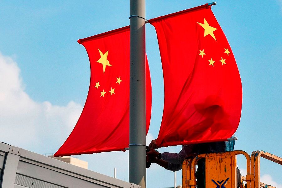 This photo taken on 24 September 2020 shows workers setting up national flags along a street ahead of the upcoming National Day in Ningbo, Zhejiang, China. (STR/AFP)