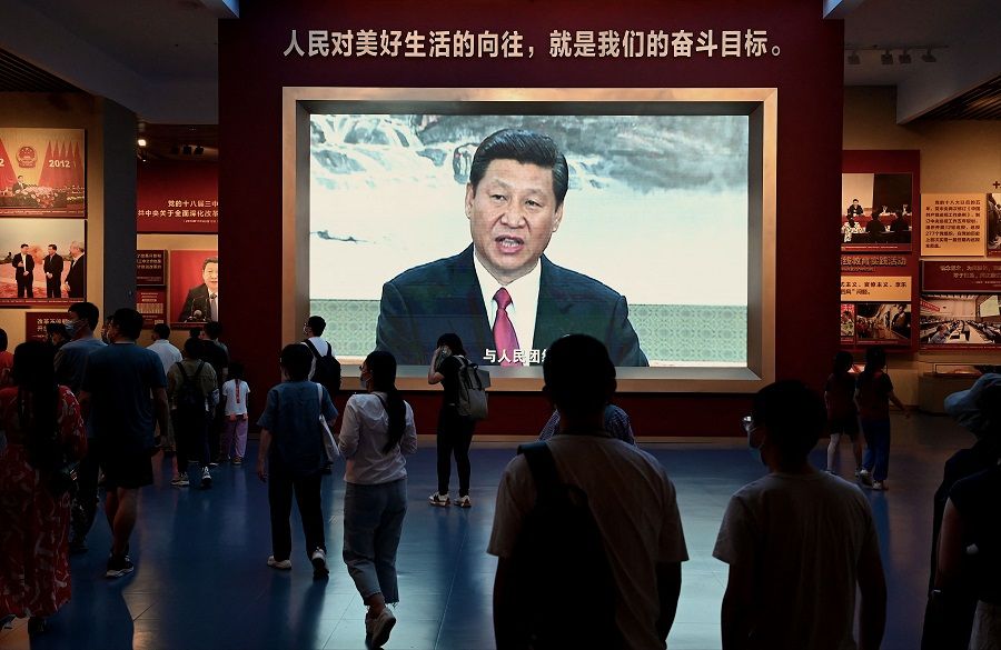 People walk past a screen showing Chinese President Xi Jinping at the Museum of the Communist Party of China in Beijing, China, on 4 September 2022. (Noel Celis/AFP)