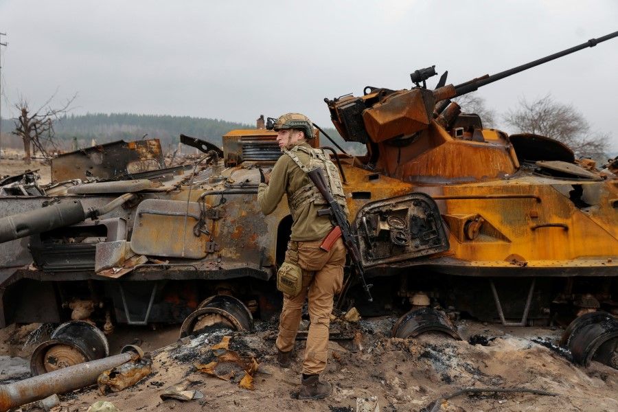 A Ukrainian service member inspects destroyed Russian BTR-82 armoured personal carrier (APC) in a village near a frontline, as Russia's attack on Ukraine continues, in Kyiv Region, Ukraine, 31 March 2022. (Serhii Nuzhnenko/Reuters)