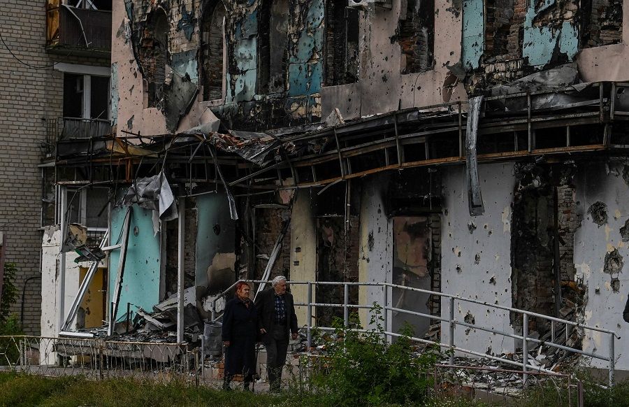 A couple walks between debris in the city of Izium, Kramatorsk, eastern Ukraine, on 11 September 2022, amid the Russian invasion of Ukraine. (Juan Barreto/AFP)