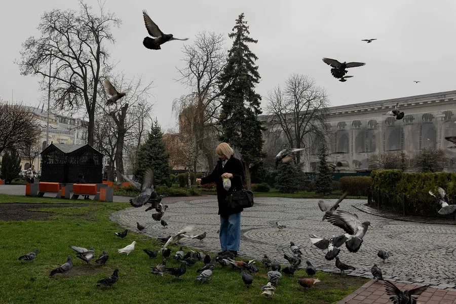 A woman feeds pigeons in a park in the Podil neighbourhood of Kyiv, on 31 March 2025, amid the Russian invasion on Ukraine.  (Tetiana Dzhafarova/AFP)