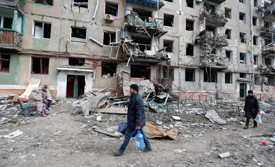 People are seen in a courtyard near a block of flats heavily damaged during the Russia-Ukraine conflict in the southern port city of Mariupol, Ukraine, 18 April 2022. (Alexander Ermochenko/Reuters)
