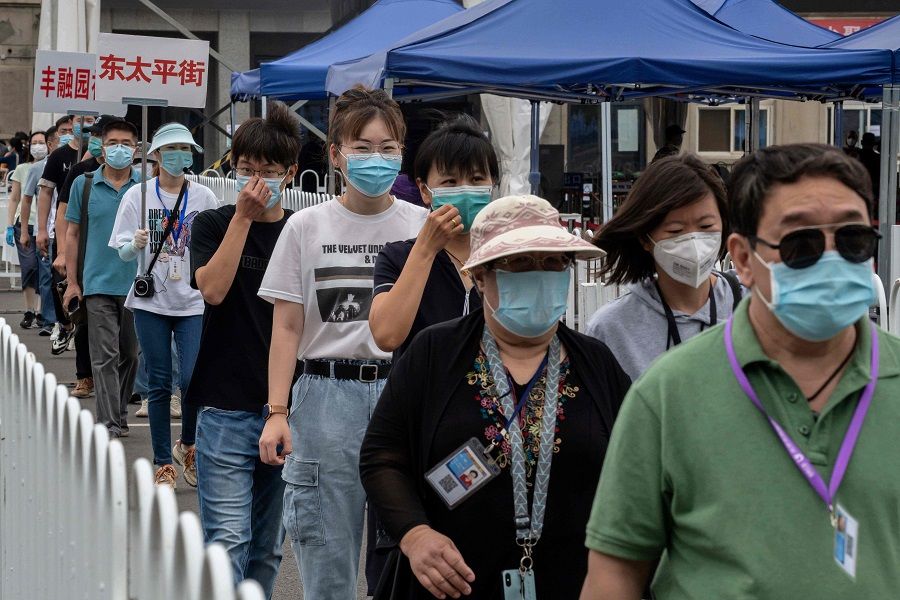 People wearing face masks gather at an outdoor area during mass testing for the Covid-19 coronavirus at the Jinrong Street testing site in Beijing on 24 June 2020. (Nicolas Asfouri/AFP)