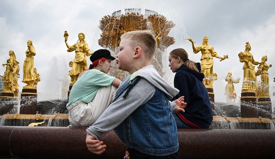 Children sit at the "Friendship of Nations" fountain, built in 1954, symbolising the friendship of sixteen Soviet republics forming the USSR, at the All-Russia Exhibition Centre (VDNKh) in Moscow, Russia on 27 May 2021. (Alexander Nemenov/AFP)