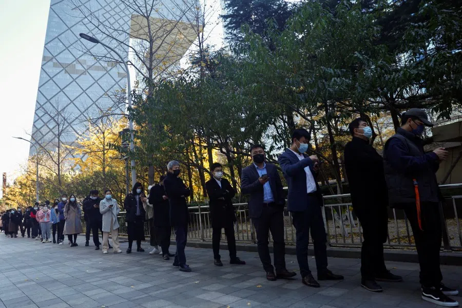 People line up to take a nucleic acid test for Covid-19 at a testing booth near an office building in Central Business District (CBD) in Chaoyang district, Beijing, China, 15 November 2022. (Tingshu Wang/Reuters)