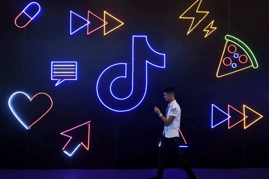 A man holding a phone walks past a sign of Chinese company ByteDance's app TikTok, in Hangzhou, Zhejiang province, China 18 October 2019. (Stringer/Reuters)