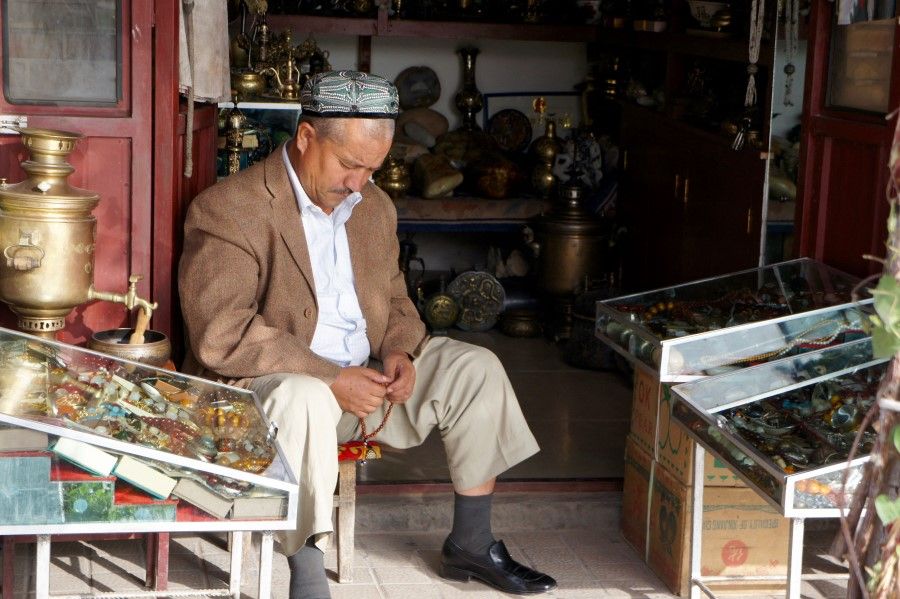 In this photo released by Gary Dyck and received by AFP on 24 April 2021, a man holds prayer beads as he sits in a shop in Kashgar in 2011. (Gary and Andrea Dyck/Family handout/AFP)