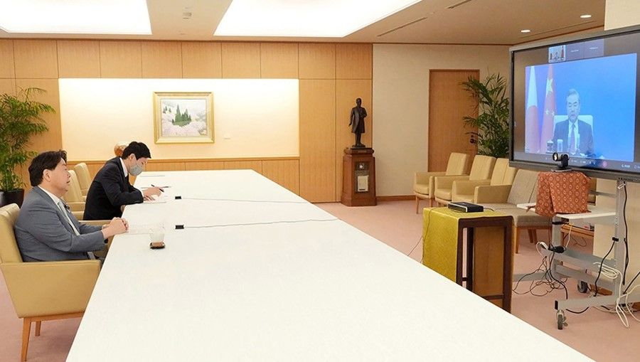 This handout picture taken and provided on 18 May 2022 by the Ministry of Foreign Affairs of Japan via Jiji Press shows Japan's Foreign Minister Yoshimasa Hayashi (left) speaking with China's Foreign Minister Wang Yi (right) via video link in Tokyo. (Handout/AFP)